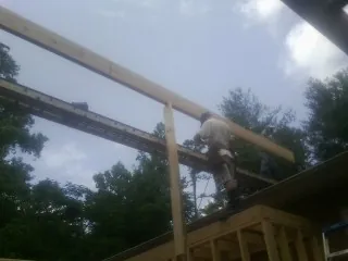 Carpenter setting a ridge beam over a new addition frame — Ice Dam Removal by Roofing Brothers in Providence