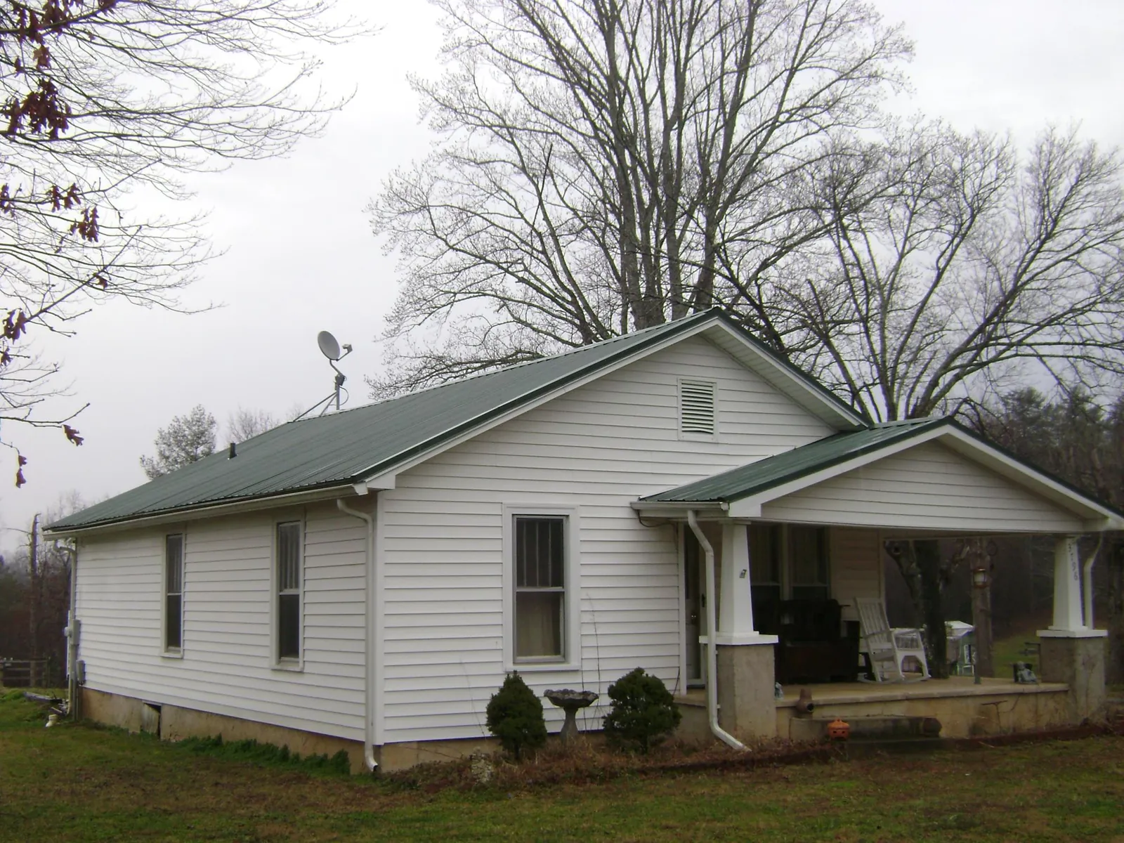Green metal roof on a white bungalow with a side porch in Providence