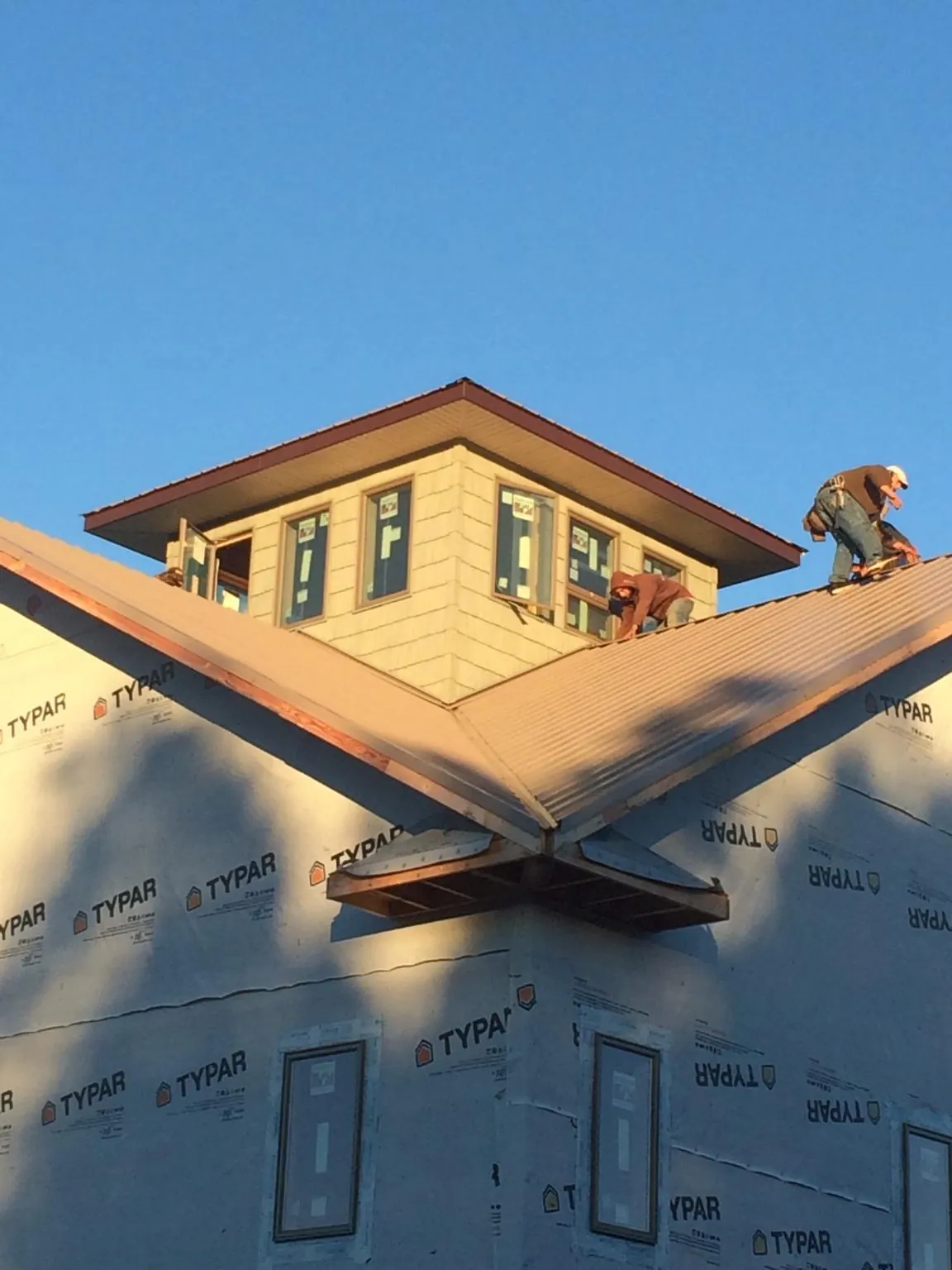 Roofers working around a rooftop cupola on a new metal roof at sunset — Roof Waterproofing in Providence by Roofing Brothers